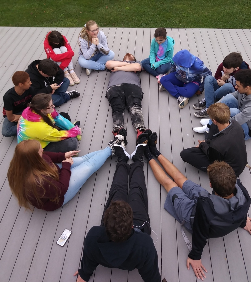 students sitting/ laying to create the Diversity Advisory Peace Symbol